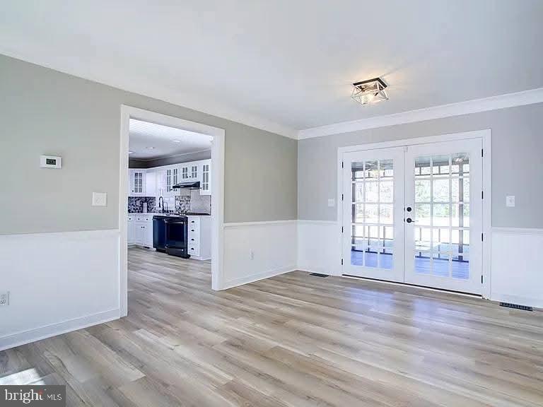 12148 Atlantic Road Temperanceville, VA 23442 - Photo 5 of 30 an empty room with wooden floor and a kitchen