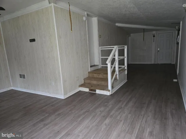 a view of an empty room with wooden floor and a sink
