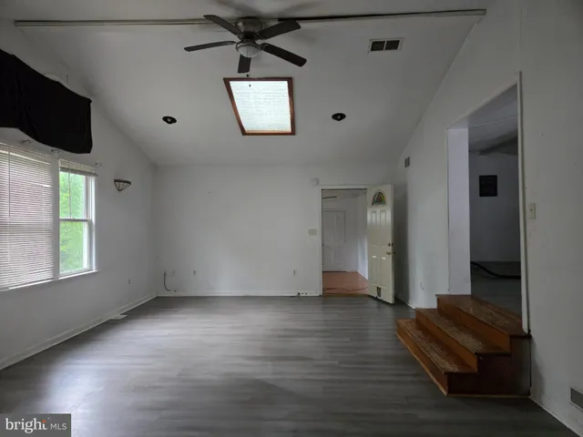 an empty room with windows and ceiling fan