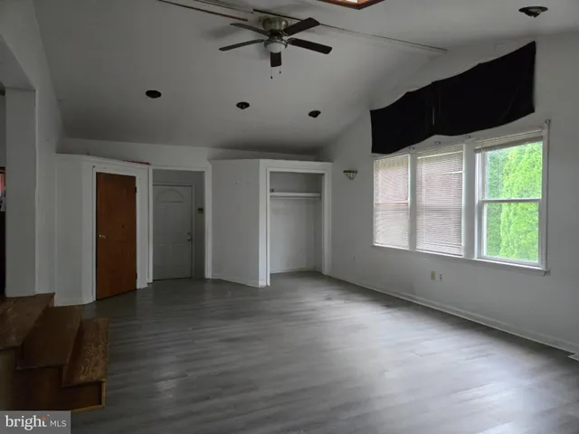 a view of an empty room with a window and wooden floor