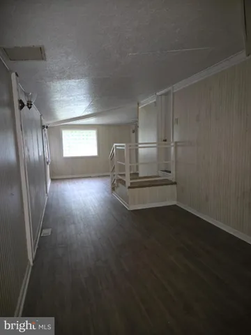an empty room with wooden floor cabinet and windows