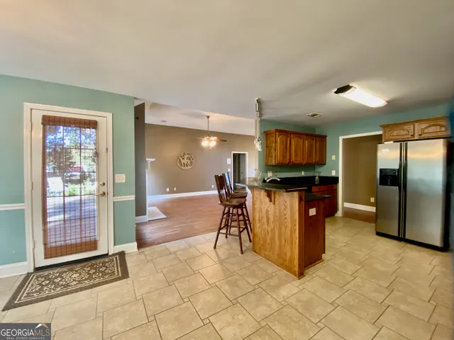 a dining hall with stainless steel appliances granite countertop a refrigerator and a sink