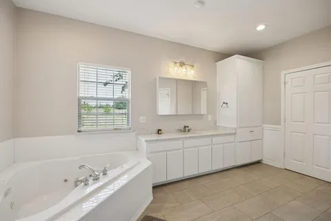 a bathroom with a tub sink and mirror