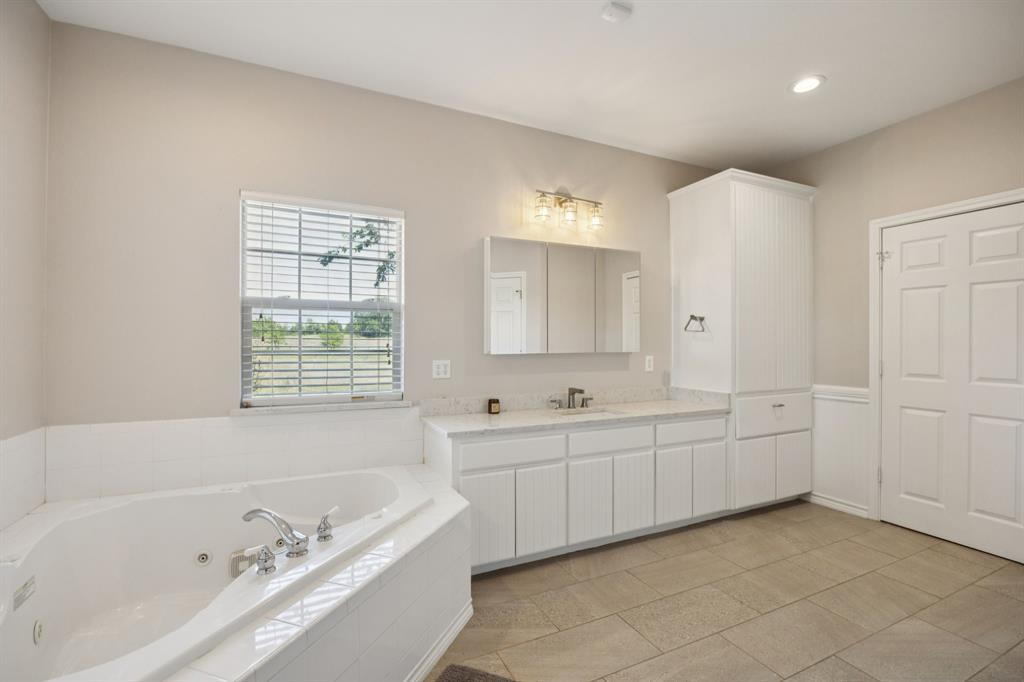 9530 County Road 581 Anna, TX 75409 - Photo 20 of 39 a bathroom with a tub sink and mirror