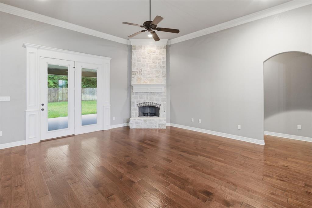 7765 Hickory Spring Lane Tyler, TX 75703 - Photo 11 of 38 Spacious living area featuring wood-finish flooring, a stone fireplace with a white mantel, and ceiling fan
