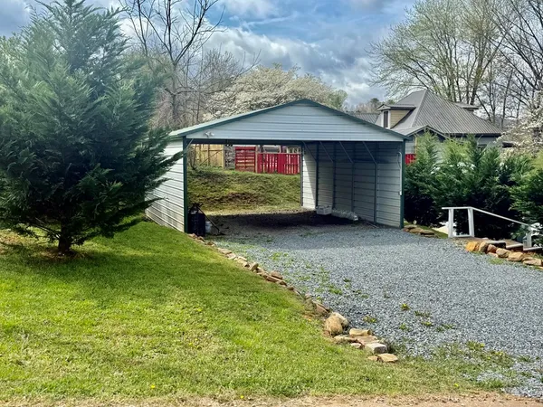 a view of a house with a yard fire pit and a large tree