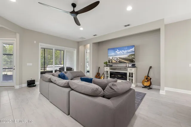 a large white kitchen with stainless steel appliances kitchen island a stove a sink a couch and a dining table with wooden floor