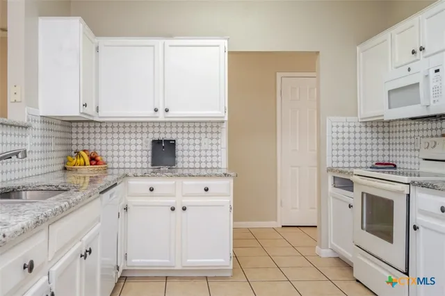 a kitchen with granite countertop white cabinets and white appliances