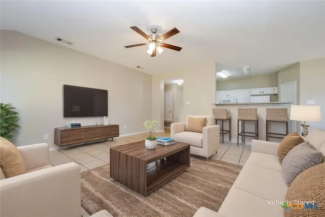 a living room with furniture kitchen view and a flat screen tv