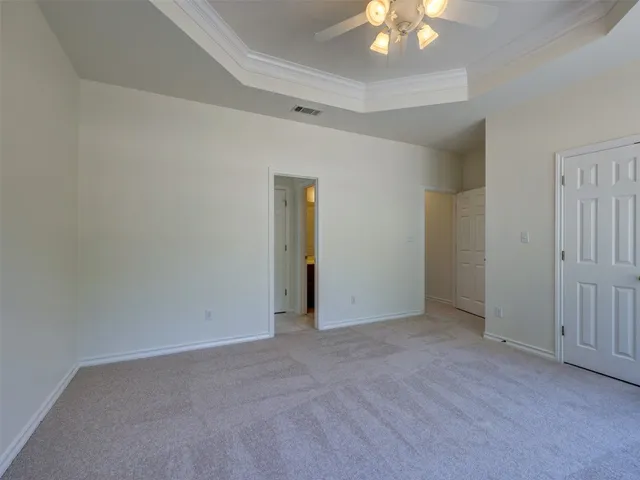 an empty room with a chandelier fan and windows