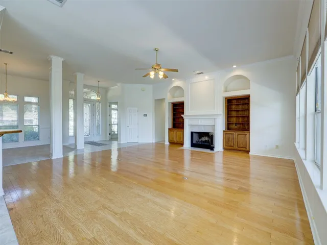 an empty room with wooden floor fireplace and windows