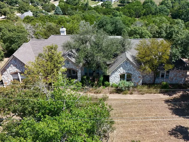 a view of a house with a yard and large trees