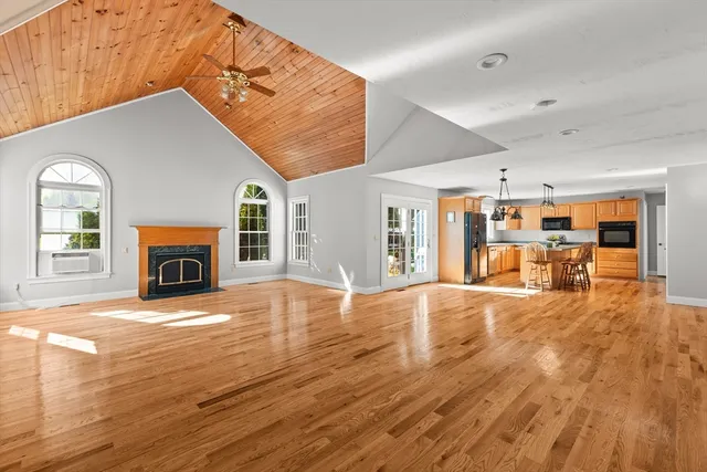 a view of an empty room with wooden floor fireplace and a window
