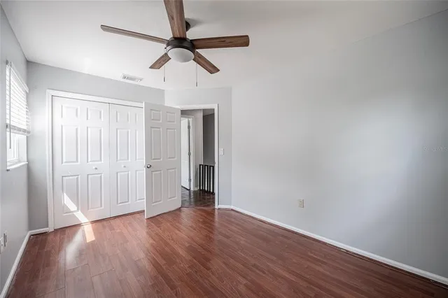 a view of empty room with wooden floor and fan