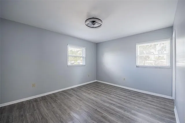 an empty room with wooden floor and windows
