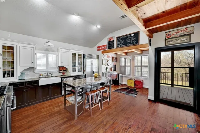 a kitchen with stainless steel appliances granite countertop a stove refrigerator and a dining table with wooden floor