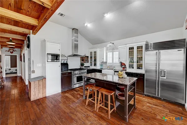 a kitchen with stainless steel appliances granite countertop a stove refrigerator and a dining table with wooden floor