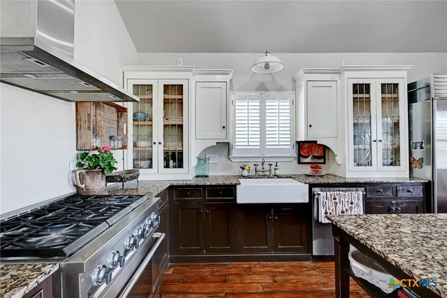 a kitchen with stainless steel appliances granite countertop a stove refrigerator and a dining table with wooden floor