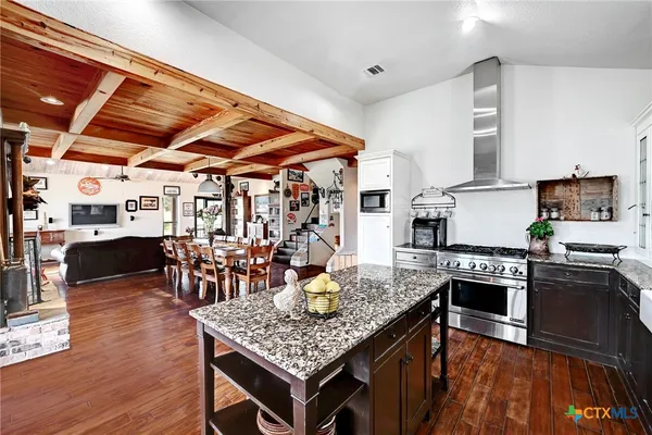 a kitchen with stainless steel appliances granite countertop a stove refrigerator and a dining table with wooden floor