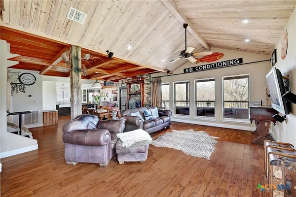 a living room with furniture a wooden floor and next to a window