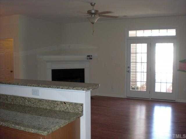 1342 Regulator Street Raleigh, NC 27603 - Photo 3 of 4 a view of an empty room with wooden floor and a fireplace