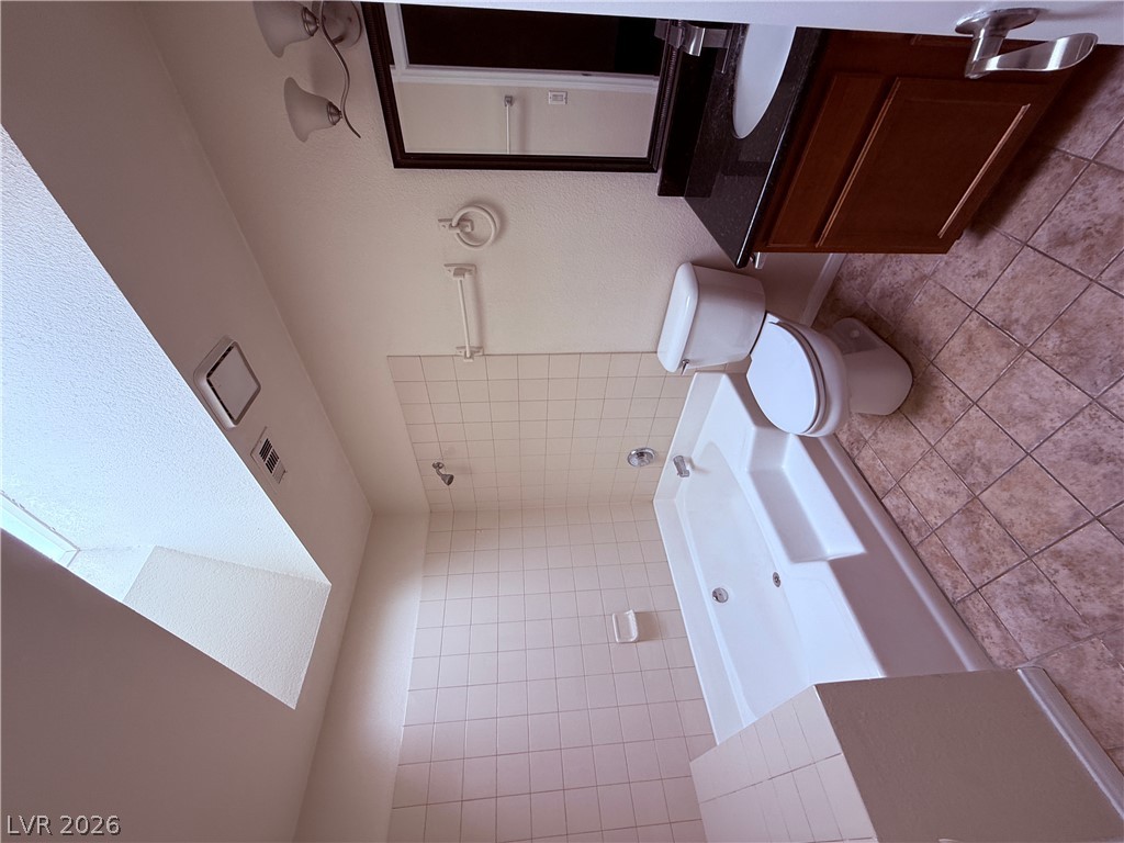 9325 West Desert Inn Road, Unit 260 Las Vegas, NV 89117 - Photo 21 of 42 A compact bathroom featuring a tiled shower, bathtub, and vanity with a dark countertop.