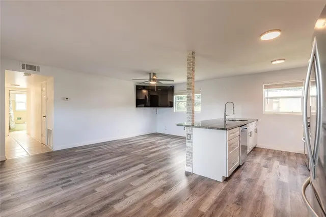 a kitchen with granite countertop a refrigerator and white cabinets