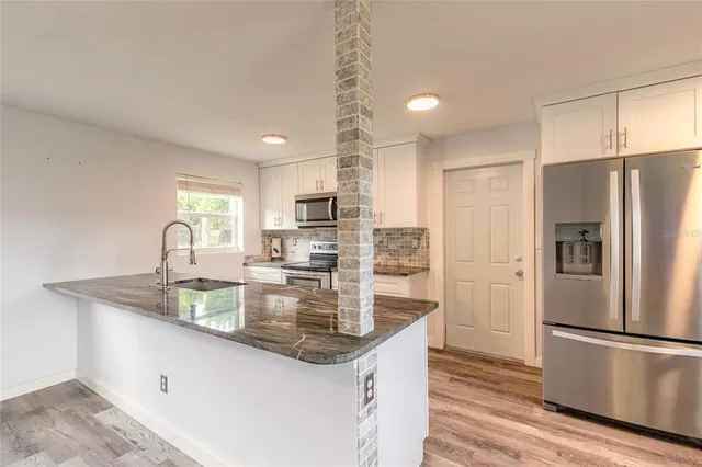 a kitchen with granite countertop a stove top oven sink and cabinets