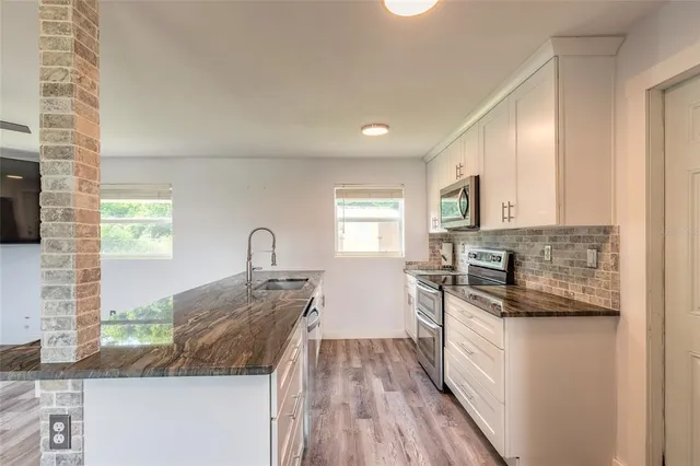 a kitchen with granite countertop a sink and a stove top oven