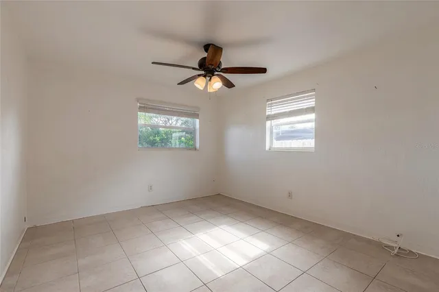 an empty room with windows and fan
