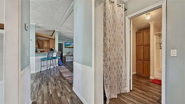 a view of a hallway with wooden floor and a bathroom
