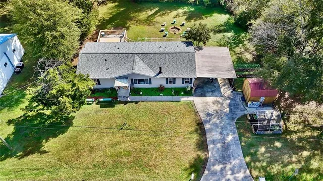 an aerial view of a house with swimming pool and large trees