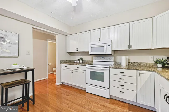 a kitchen with granite countertop white cabinets and white appliances