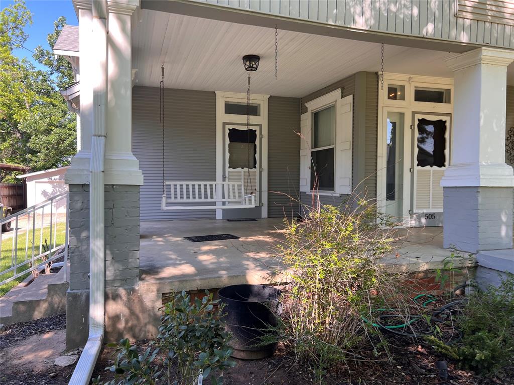 505 North Elm Street Comanche, TX 76442 - Photo 32 of 40 a view of a house with a small yard and floor to ceiling window and potted plants