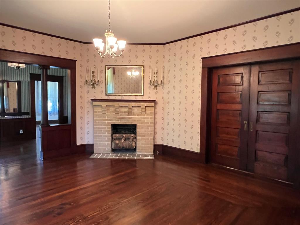 505 North Elm Street Comanche, TX 76442 - Photo 6 of 40 a view of a livingroom with a fireplace a chandelier and hardwood floor