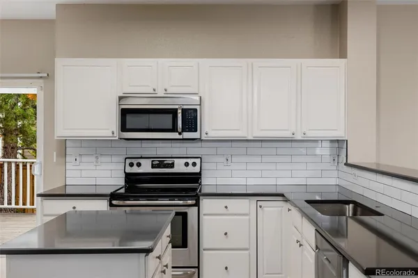 a kitchen with granite countertop a sink stove and microwave