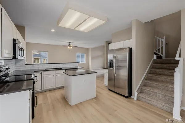 a kitchen with stainless steel appliances granite countertop a refrigerator a stove and a sink