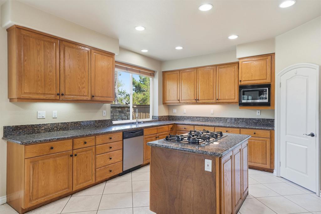 2612 Coyote Ridge Terrace Chula Vista, CA 91915 - Photo 18 of 57 a kitchen with stainless steel appliances granite countertop a stove a sink dishwasher and a refrigerator with wooden floor