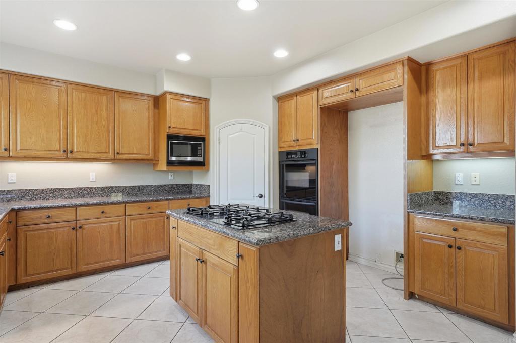 2612 Coyote Ridge Terrace Chula Vista, CA 91915 - Photo 19 of 57 a kitchen with granite countertop cabinets and stove top oven