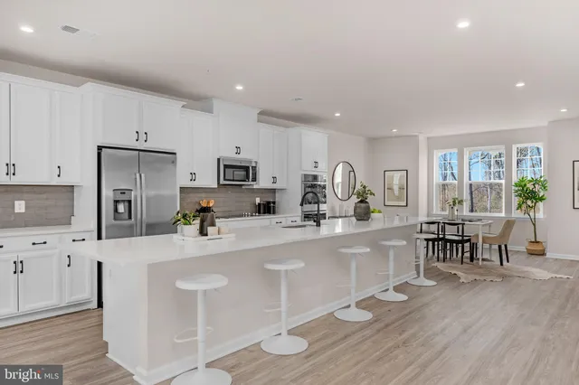 a large white kitchen with lots of counter space a sink and appliances