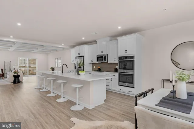 a kitchen with stainless steel appliances kitchen island granite countertop a stove a sink a refrigerator and white cabinets with wooden floor