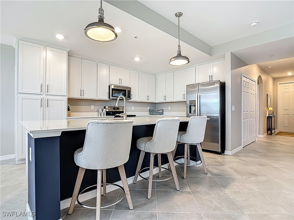 43981 Boardwalk Loop, Unit 2222 Punta Gorda, FL 33982 - Photo 18 of 50 a kitchen with stainless steel appliances kitchen island granite countertop a dining table chairs refrigerator and microwave