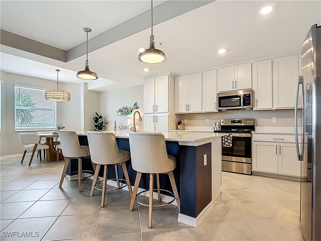 43981 Boardwalk Loop, Unit 2222 Punta Gorda, FL 33982 - Photo 7 of 50 a kitchen with stainless steel appliances granite countertop a stove a sink a microwave a refrigerator and a dining table with wooden floor