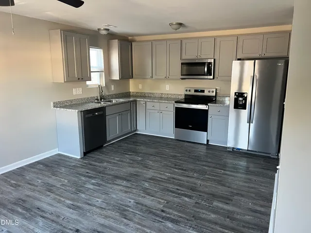 a kitchen with granite countertop a refrigerator and a stove top oven