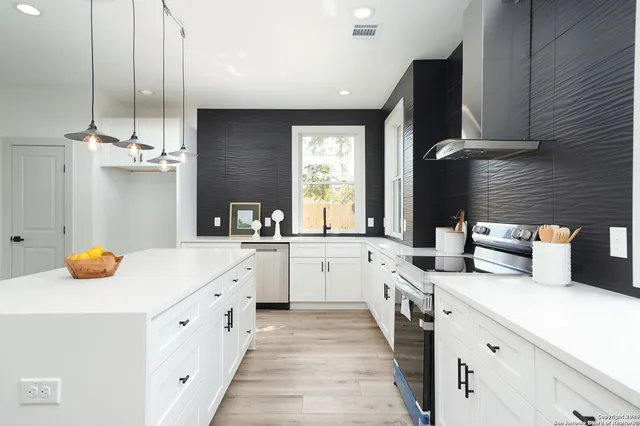 a large white kitchen with a window wooden floor and stainless steel appliances