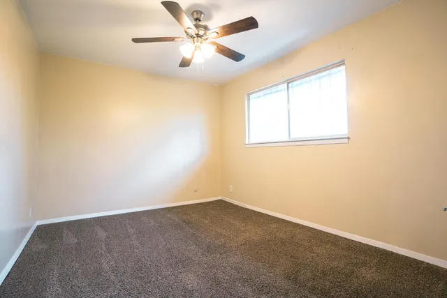 an empty room with a window and a fan