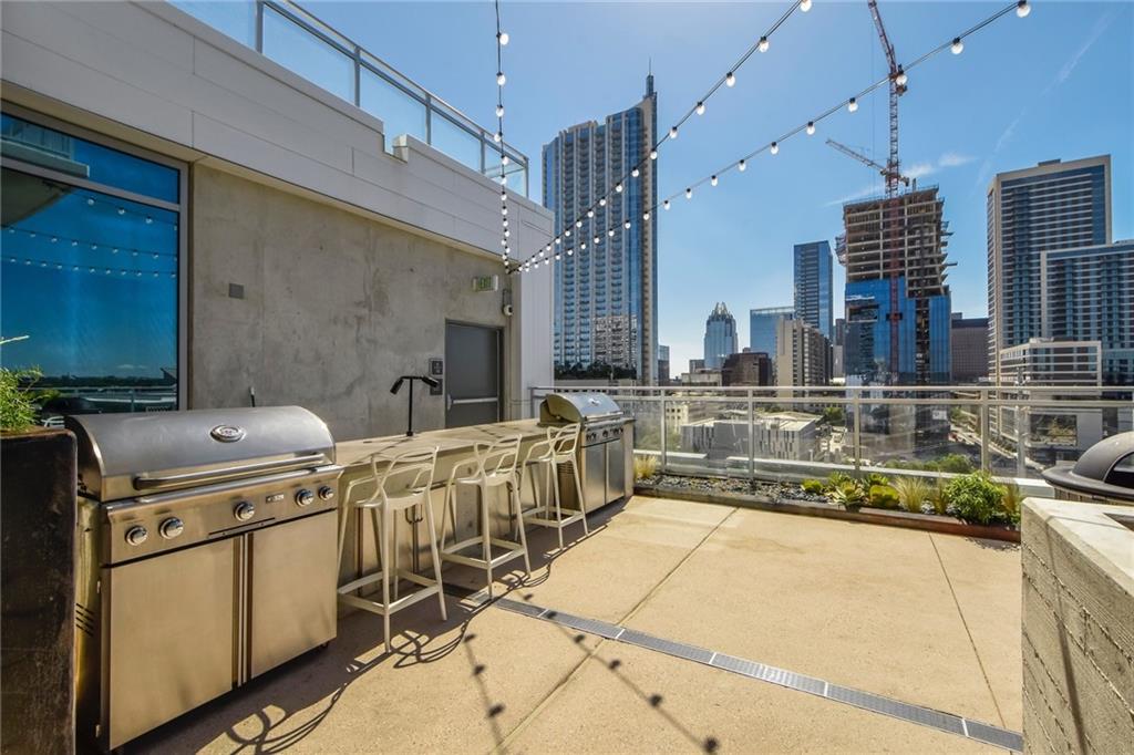 222 West Avenue, Unit 2207 Austin, TX 78701 - Photo 16 of 30 Rooftop patio featuring multiple stainless steel grills, a built-in outdoor bar with bar stools, string lighting, and extensive hardscaping