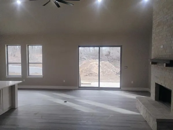 an empty room with windows and fireplace