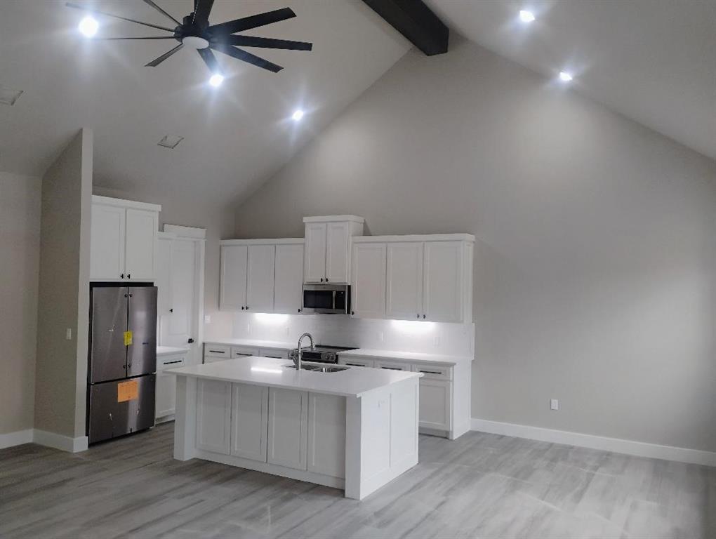146 Hauser Place Runaway Bay, TX 76426 - Photo 4 of 15 a kitchen with kitchen island white cabinets and stainless steel appliances