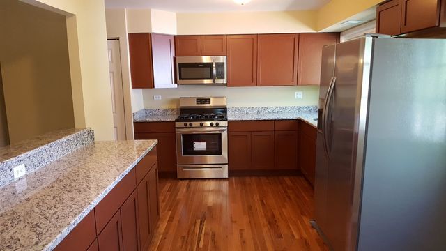 457 Galahad Road Bolingbrook, IL 60440 - Photo 3 of 14 a kitchen with stainless steel appliances granite countertop a refrigerator a stove top oven and wooden floor
